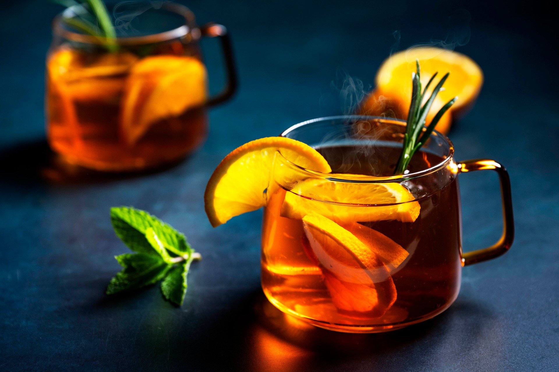 Autumn or winter alcoholic hot cocktails with orange slices in glass mugs